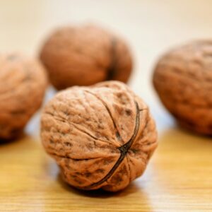 Macro shot of whole walnuts on a wooden surface, emphasizing texture.